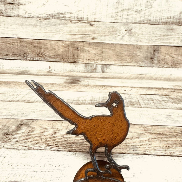 Rusty metal roadrunner cutout on a stand with a red bandana around its neck