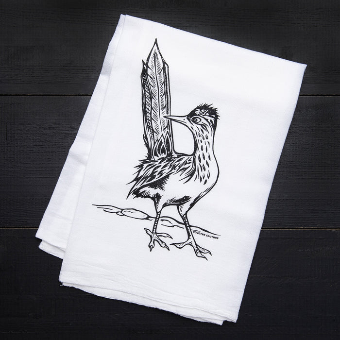White tea towel on a dark surface featuring a bold roadrunner illustration and Counter Couture text