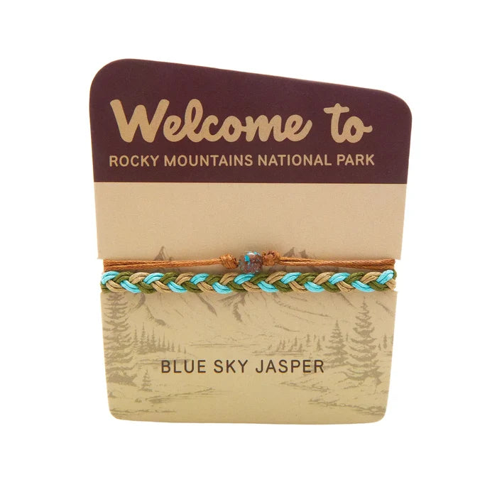Turquoise, olive, and tan braided bracelet with a small blue bead on a Rocky Mountains National Park welcome card