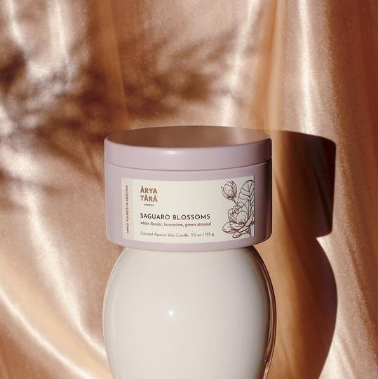 Saguaro Blossoms candle in pale pink tin with label against a silky pink backdrop.
