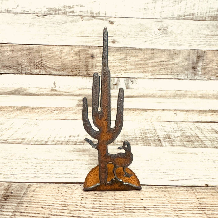 Rusty metal standee shaped as a tall saguaro cactus with a road runner at its base.