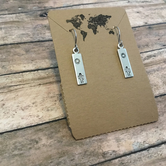 Saguaro cactus motif dangle earrings with rectangular silver charms turquoise bead accents on a brown card