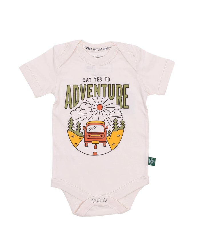 Pale pink infant onesie with Say Yes to Adventure graphic showing a red car on a road with mountains and trees