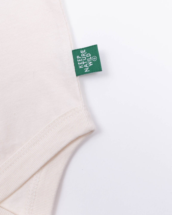 Close up of pale pink onesie neck area with green Keep Nature Wild tag.