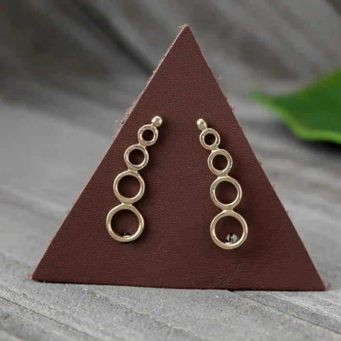 Silver stacked circle ear climbers with three connected rings on a brown triangular display