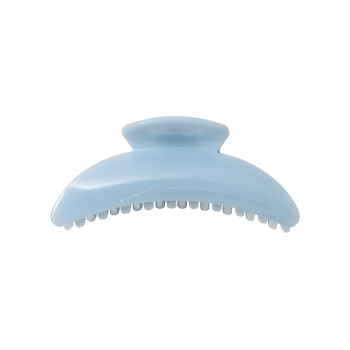 The Slim Hair Claw Clip — Mist by Karst Essentials is a slim, sky blue cellulose acetate clip with a curved shape and interlocking teeth, displayed on a white background.