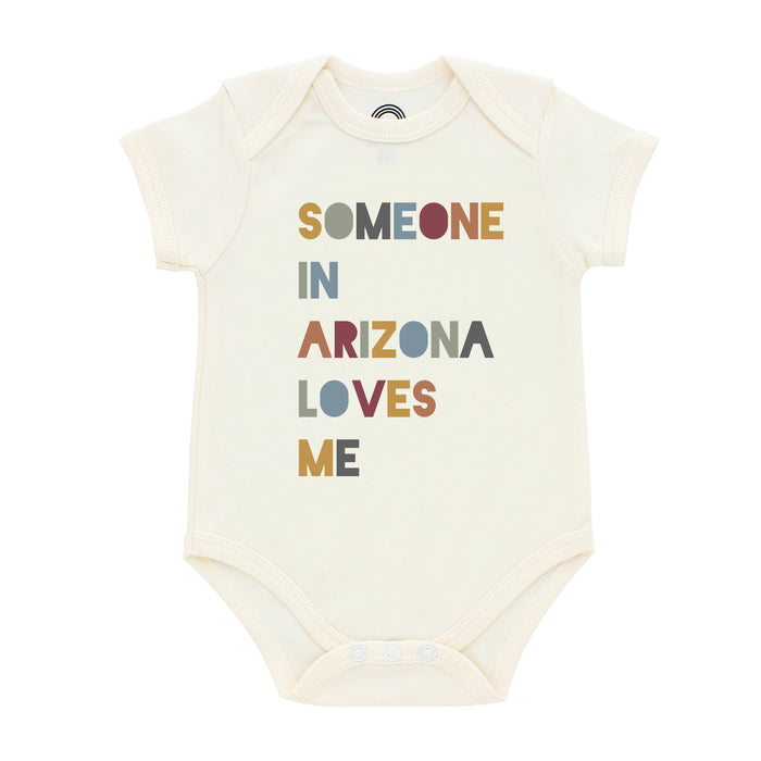 Cream baby onesie with multicolored letters spelling SOMEONE IN ARIZONA LOVES ME