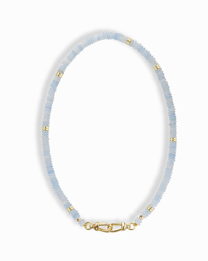 The Sonia Gemstone Necklace by Mod + Jo features light blue aquamarine beads, gold spacer accents, and a gold clasp—a stunning piece of handmade jewelry.