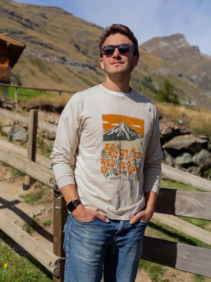Man wearing Spring Fever long sleeve beige shirt with mountain and floral print outdoors beside a wooden railing