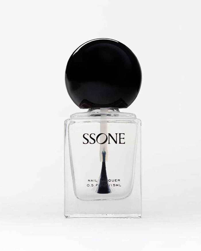 Clear nail polish in bottle with black cap on a white background