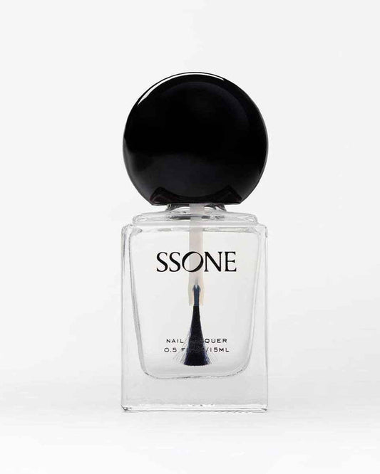 Clear nail polish in bottle with black cap on a white background