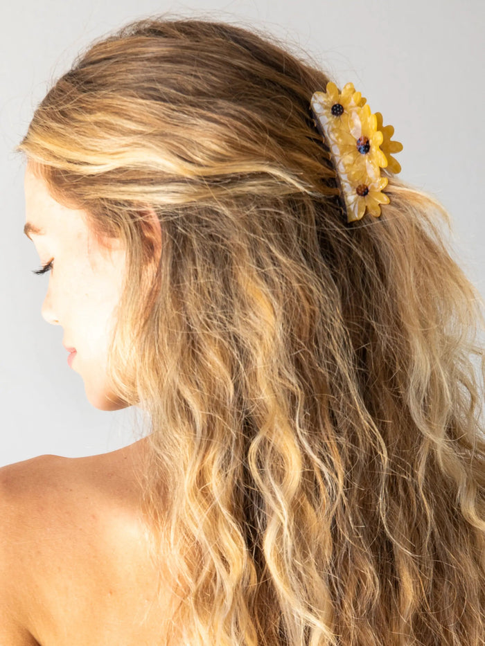 Side view of a woman wearing a yellow sunflower claw clip in her hair