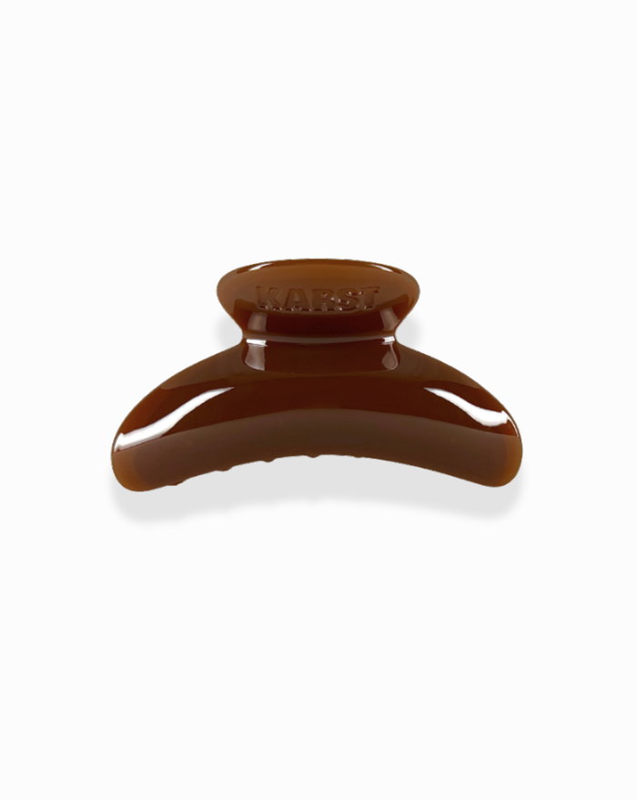 The SuperClip Hair Claw is a durable brown plastic clip with a curved wide grip and rounded edges, shown against a white background.