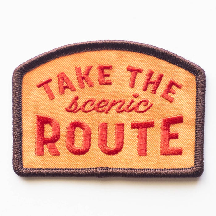Close-up of orange embroidered patch with TAKE THE scenic ROUTE and a dark brown border
