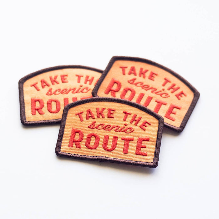 Three orange embroidered patches with TAKE THE scenic ROUTE and brown borders arranged together