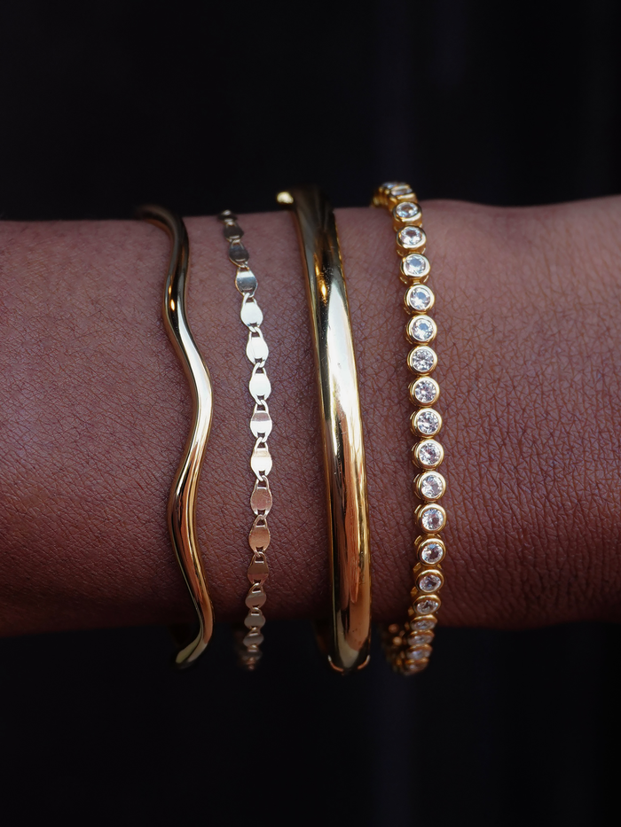 Close-up of Tate Dome Bangle worn with other gold bracelets showcasing jewelry styling and wrist adornment.