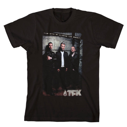 Black T-shirt by Thousand Foot Krutch featuring a printed photo of three men in front of a wall, with “The End Is Where We Begin” above and the TFK logo below the image.