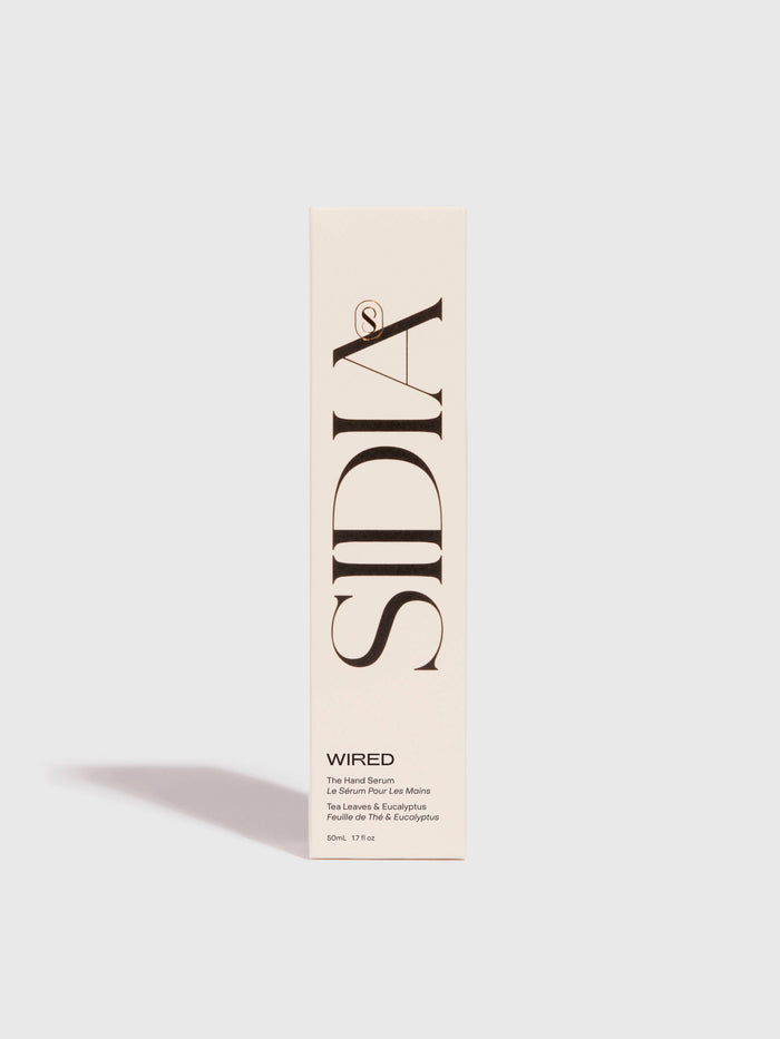 A cream-colored rectangular box stands upright, featuring large vertical black "SIDIA" branding. At the bottom, it reads "WIRED" and notes The Hand Serum by SIDIA—a lightweight, fast-absorbing hand serum—against a plain light background.