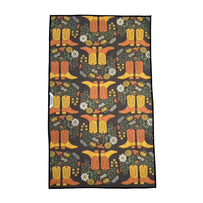 Western Bloom kitchen towel with yellow boots and white flowers among greenery on a dark background
