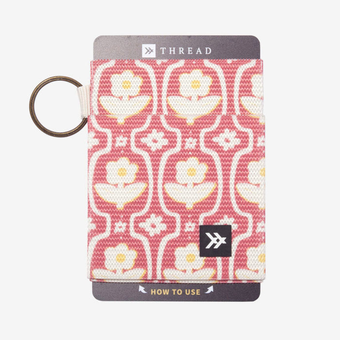 Pink and white patterned fabric wallet with a metal key ring.