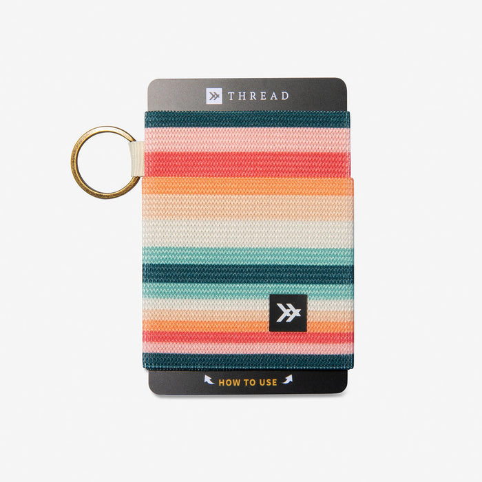Bright striped elastic wallet featuring warm pink orange and teal stripes with a logo patch and key ring.
