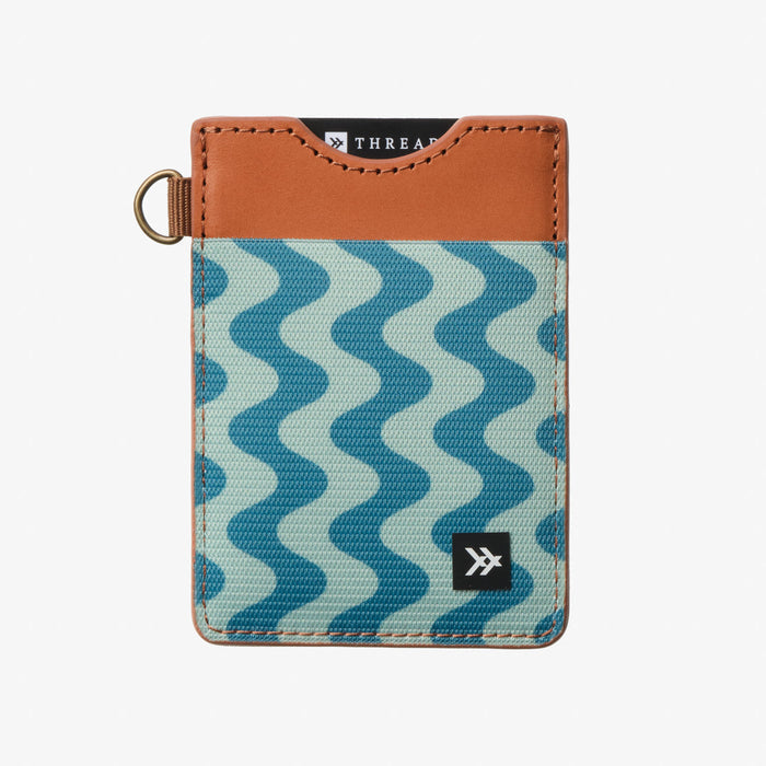 Tan leather and blue wave patterned wallet with stitched edges and a small logo at the bottom corner