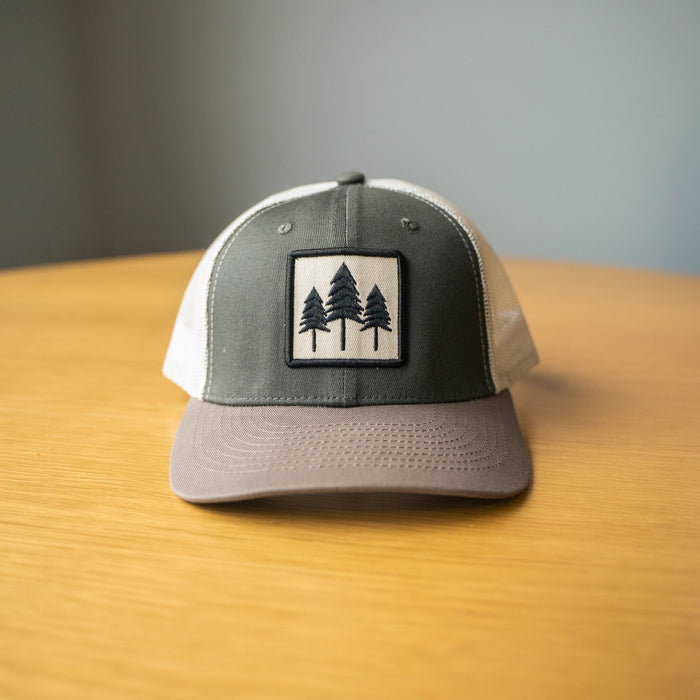Three Tree Tri Tone Trucker hat in grey and brown with a front patch showing three pine trees