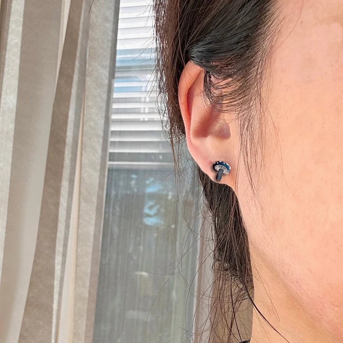 Close up of an ear wearing a navy blue Mushroom earring from the Groovy Mushrooms collection.