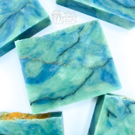 Marbled turquoise soap bar with blue and teal swirls and a Wild Women Soaps watermark