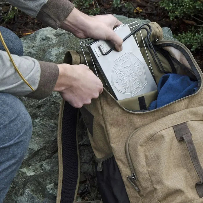 Lifestyle image of UCO Mini Flatpack grill and firepit being packed in a rucksack