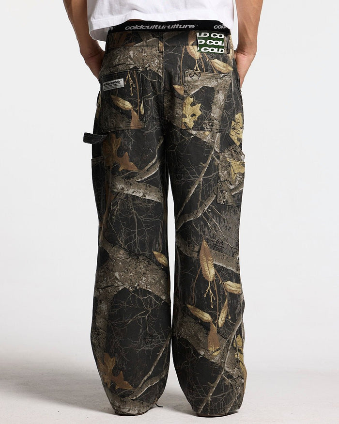 V1 CARPENTER PANTS REALTREE BLACK - black realtree camo carpenter pants, back view on male model - Cold Culture
