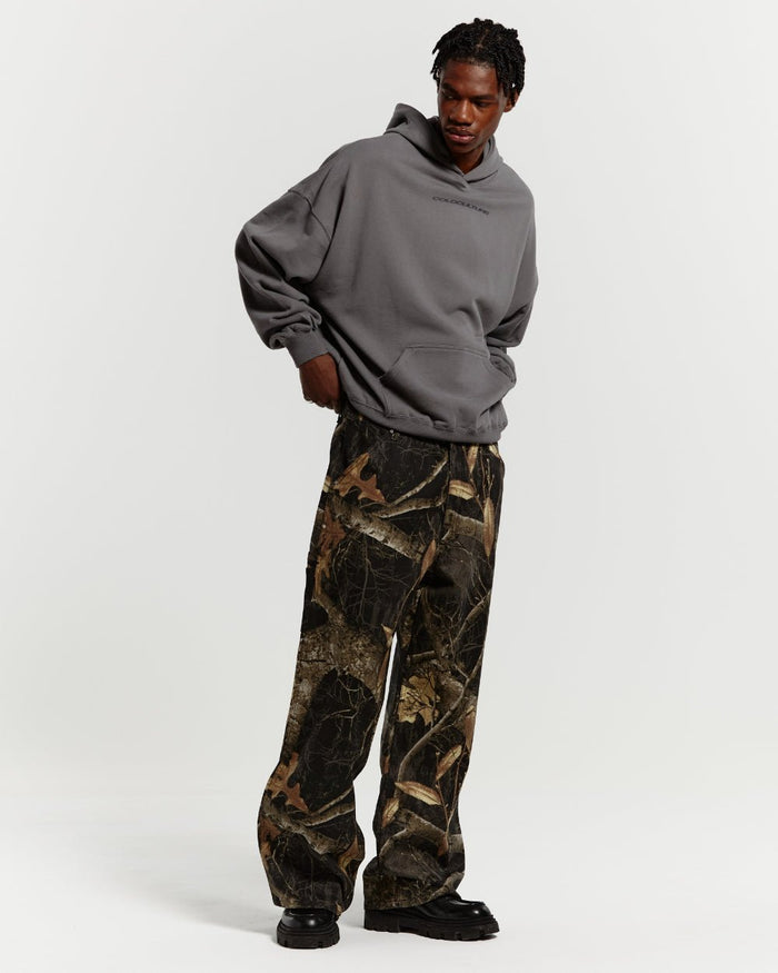 V1 CARPENTER PANTS REALTREE BLACK - black realtree camo carpenter pants, front view on male model - Cold Culture #man