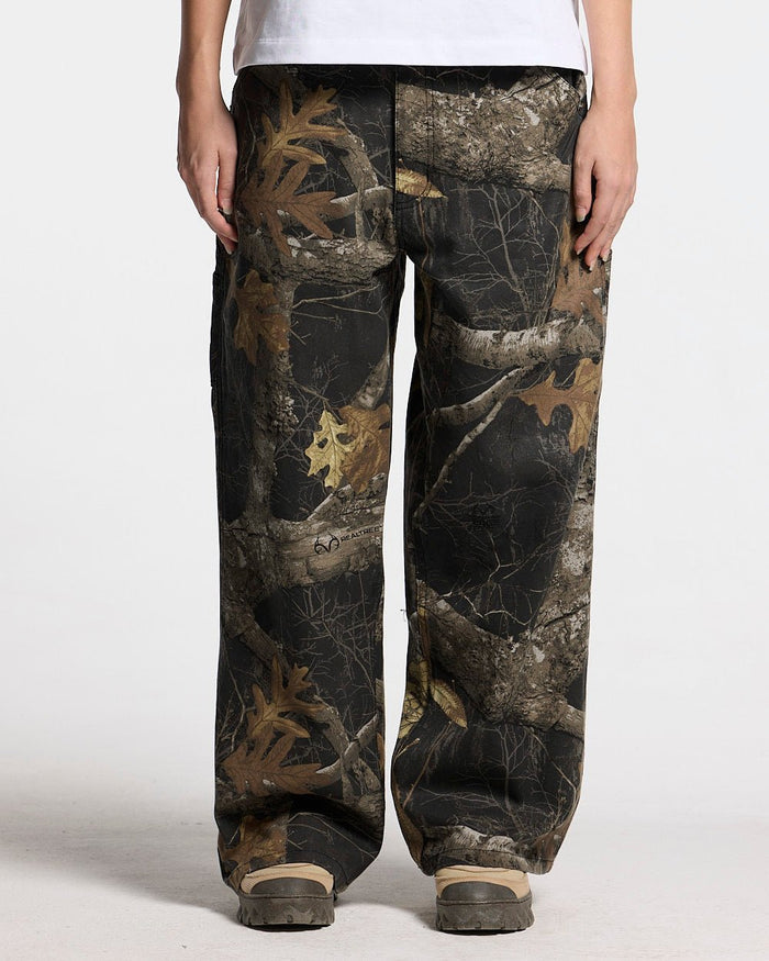 V1 CARPENTER PANTS REALTREE BLACK - black realtree camo carpenter pants, front view on female model - Cold Culture