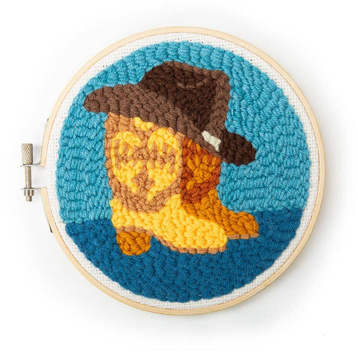 Close up of a dog in a punch needle artwork inside a wooden embroidery hoop with a brown hat and yellow body