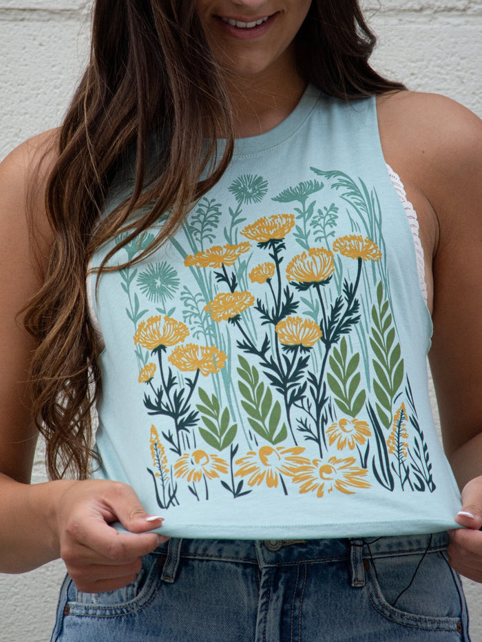 Light blue crop tank top with a yellow and green floral print worn by a model