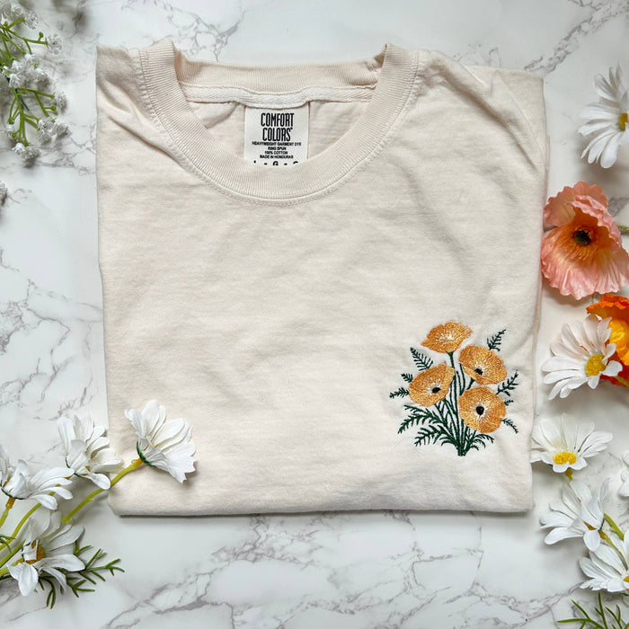 Cream Wild Poppies embroidered boxy crop tee with orange floral embroidery and visible label.