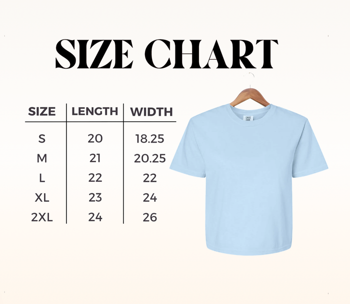Light blue boxy cropped tee on a wooden hanger beside a large size chart illustration.