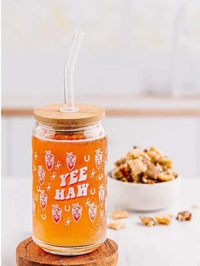 Yee Haw glass can with straw and a wooden lid filled with orange beverage.